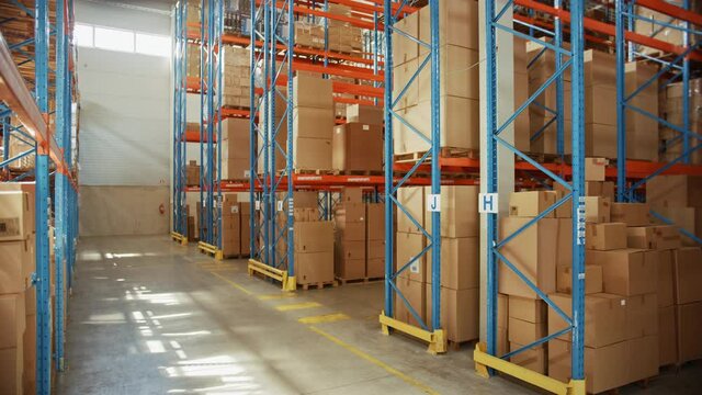 Gigantic Sunny Retail Warehouse full of Shelves with Goods in Cardboard Boxes. Logistics and Distribution Storehouse Center for further Product Delivery Packages. Descending Semi Side Camera View