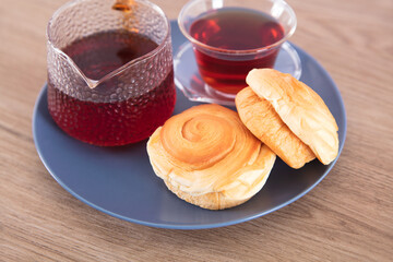 Black tea and small bread in blue plate