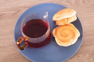 Black tea and small bread in blue plate