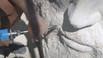 Stone Carving - Stone Carver Carving And Shaping The Mouth Part Of A Sculpture Using An Air Pneumatic Chisel.  - close up shot