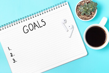The inscription goals in a notebook on blue background top view.