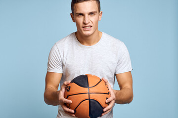 Man with a basketball ball on a blue background sport game model white t-shirt energy