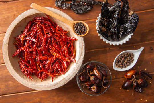 Taz&oacute;n de madera con chiles secos y especias en detalle en mesa de madera