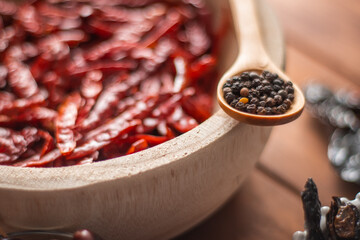 Tazón de madera con chiles secos y especias en detalle en mesa de madera