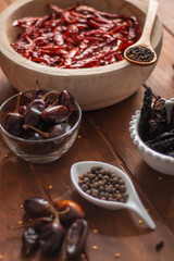 Tazón de madera con chiles secos y especias en detalle en mesa de madera