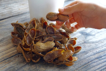 Hand holding a boiled peanut over a table with empty peanut shells
