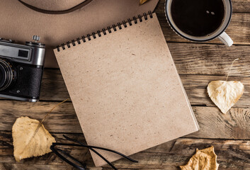 Autumn accessories flat lay. Hat, brown sweater, notebook, cup of coffee, eyeglasses, retro camera