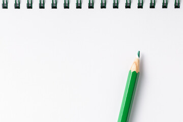 open notebook with green pencil on white table