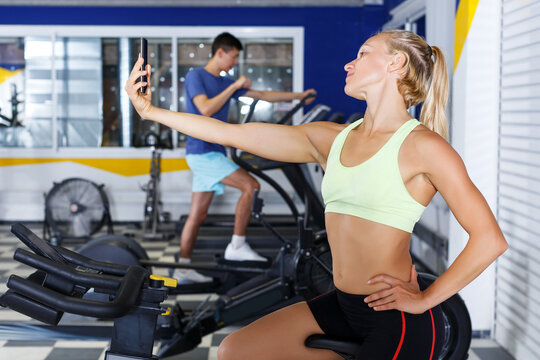 young female athlete taking selfie during training in fitness center