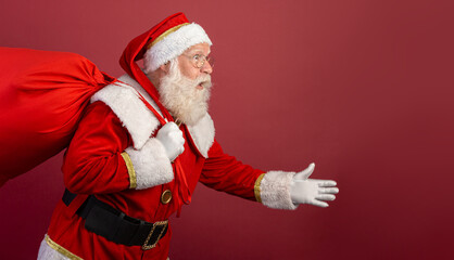 Fototapeta na wymiar Santa Claus walking on red background with copy space.
