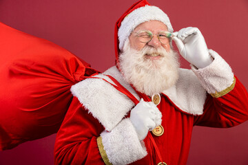 Santa Claus looking at the camera. Christmas is coming. Merry Christmas. Santa is watching. Holding his glasses.