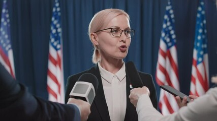 Medium portrait shot footage of mature female candidate for USA presidency giving interview to journalists