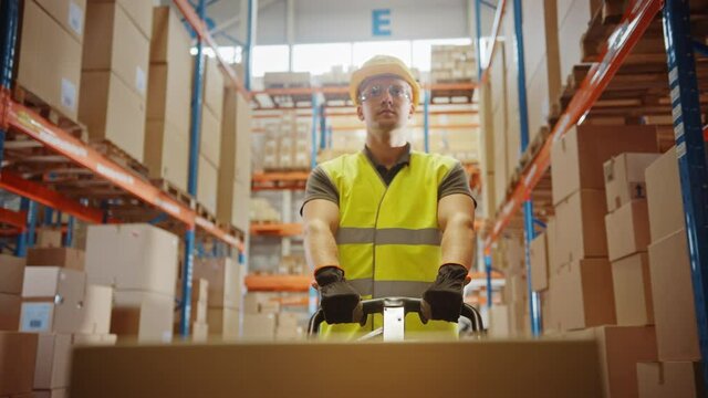 Worker Moves Cardboard Boxes using Hand Pallet Truck, Walking between Rows of Shelves with Goods in Retail Warehouse. People Work in Product Distribution Logistics Center. Point of View Shot