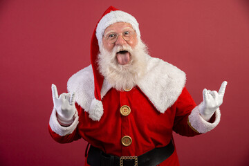 Santa Claus making rock n roll sign with hands and red background.