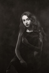 Naklejka premium Vintage portrait with harsh light of a beautiful, slim brunette woman with bright makeup and wavy hair