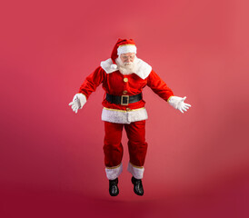 Santa Claus jumping on red background with copy space.
