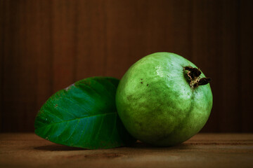 green guava with leaf on a wooden background