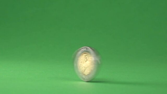 A Mexican coin of 5 pesos quickly spinning on a chroma background.