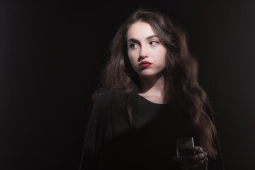 Fototapeta premium Vintage portrait with harsh light of a beautiful, slim brunette woman with bright makeup and wavy hair