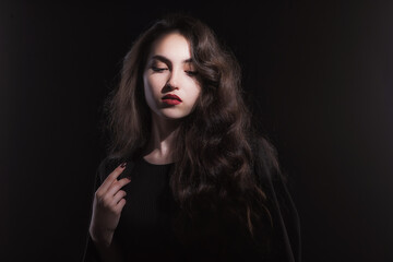 Fototapeta premium Vintage portrait with harsh light of a beautiful, slim brunette woman with bright makeup and wavy hair