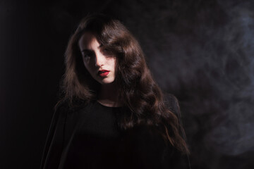 Vintage portrait with harsh light of a beautiful, slim brunette woman with bright makeup and wavy hair