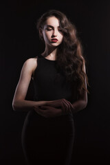 Naklejka premium Vintage portrait with harsh light of a beautiful, slim brunette woman with bright makeup and wavy hair