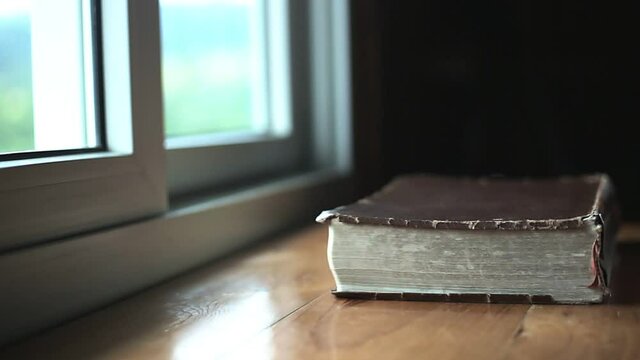Close up holy Bible on wooden table at window, Religion concept.