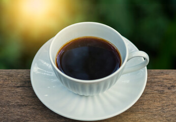 A beautiful set of white coffee mugs on a wooden table in a natural setting in the morning.