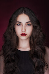 Portrait of a young brunette with lush wavy hair and beautiful highlights in the eyes