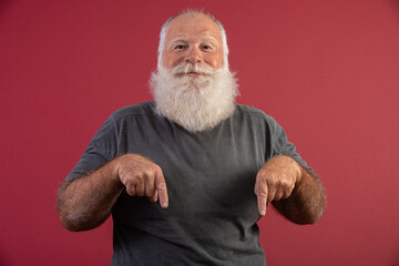 Old man with a long beard on a red background. Senior with full white beard. Old man with a long beard. Showing down.