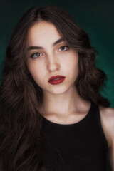 Fototapeta premium Portrait of a young brunette with lush wavy hair and beautiful highlights in the eyes