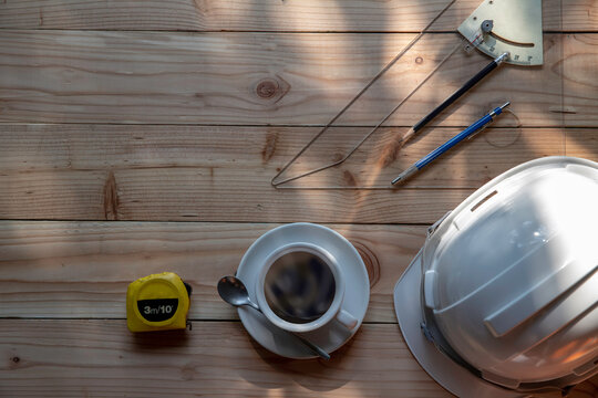  Top View Of Measuring Tape, Cup Of Coffee And White Construction Helmet And Pencil. On Wooden