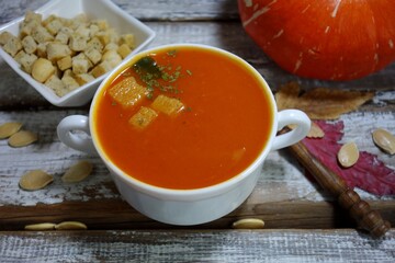 Pumpkin cream soup.  Tasty and nutritious pumpkin soup in white bowl and croutons and puff pastry - selective focus