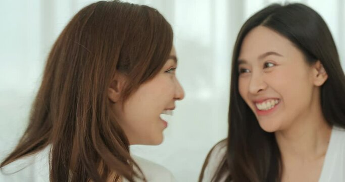 Two young lady talking with funny emotion. She gossip some secret to her friend with smiling at home.