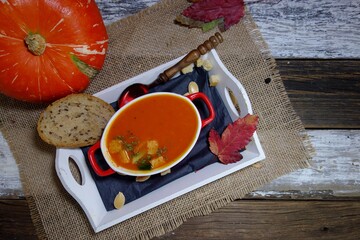 Pumpkin cream soup.  Tasty and nutritious pumpkin soup in white bowl and croutons and puff pastry - selective focus