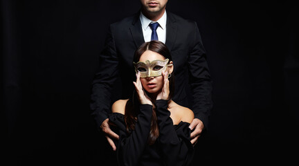 beautiful woman in mask in the hands of man in a suit