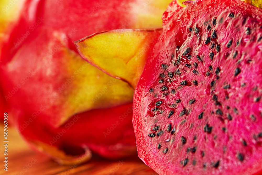 Poster Dragon fruit - pitahaya Cut into pieces on a wooden stand on a black wooden background