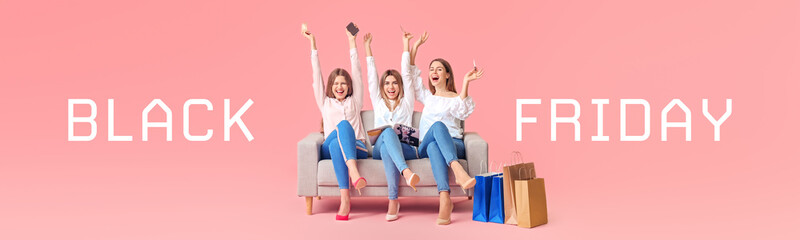 Obraz premium Young women with shopping bags sitting on sofa against color background. Black Friday sale