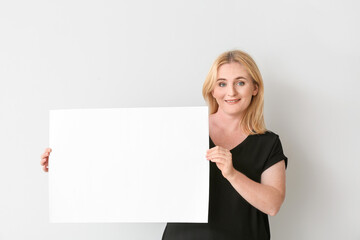 Fototapeta premium Woman with blank paper sheet on grey background