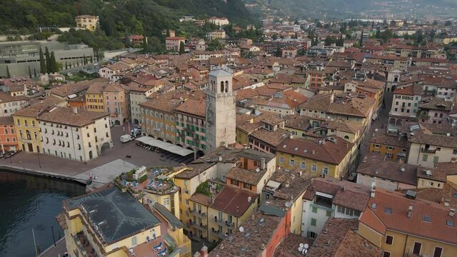 Torre Apponale, Riva Del Garda City, Italy. Aerial View of 13th Century Landmark Clock Tower and Piazza on Summer Morning, Tilt Down Drone Shot