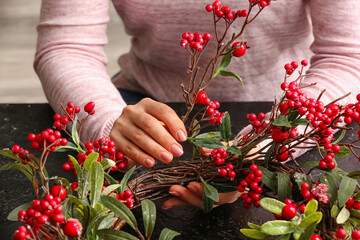 Fototapeta na wymiar Woman making beautiful Christmas wreath at table, closeup