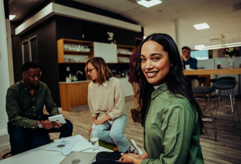 Mixed race female manager smiling while colleagues discuss project work preparing for business meeting in conference room 
