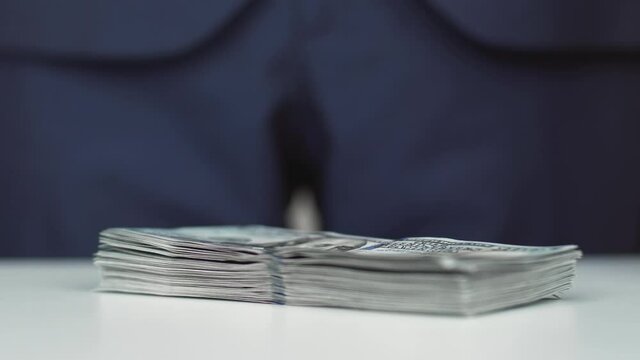 Man throws a stack of 100 american dollars money on the tabble. Bribe, corruption concept. Successful deal for a banker or businessman. Currency exchange of one hundred usd bills