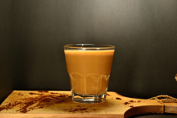 a glass of coffee milk on a black background