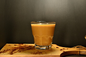 a glass of coffee milk on a black background