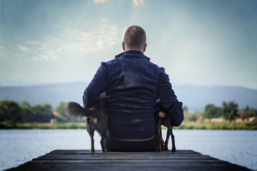 Portrait Mann sitzt mit Hunden auf Steg Brücke und schaut in die Ferne