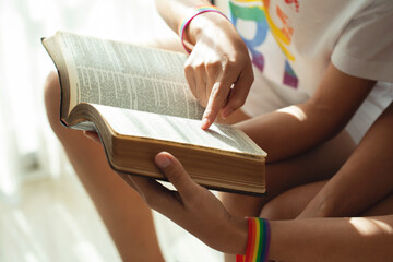 Beautiful young women LGBT lesbian sitting on sofa reading book together.Moments Happiness Concept