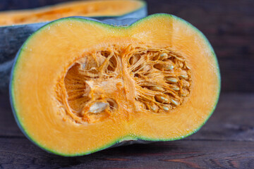 A ripe pumpkin, with bright orange flesh, cut in half on an old wooden table.