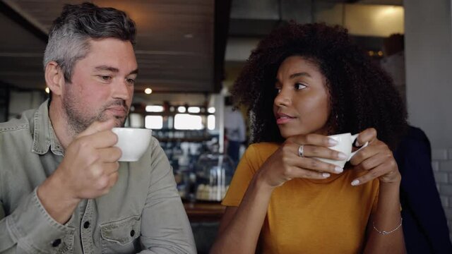 Couple having serious conversations while drinking coffee sitting in funky cafe 