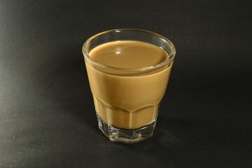 a glass of coffee milk on a black background